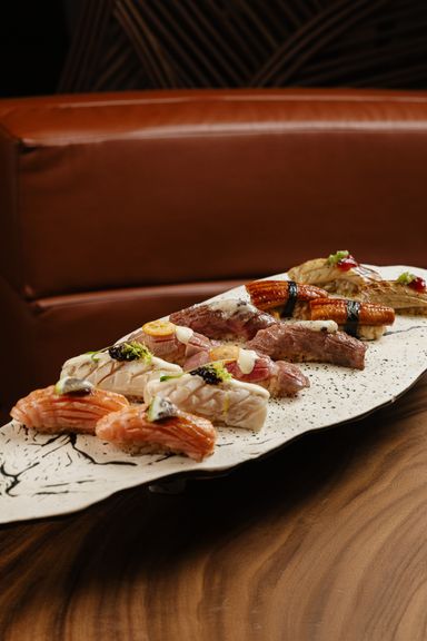 Nigiris de salmón flambeado, pescado blanco, wagyu y anguila sobre una bandeja blanca